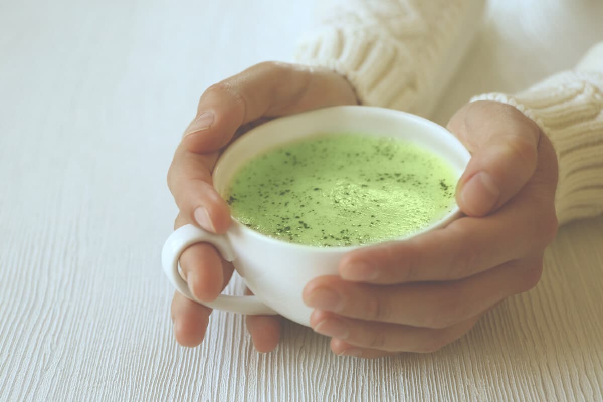 person holding a cup of green tea